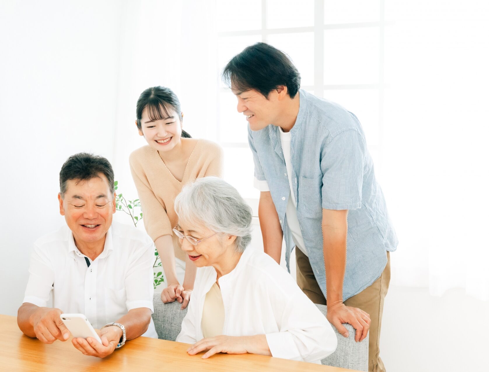 リビングで和やかにスマホを眺めるあたたかい三世代家族